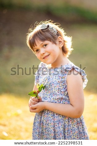 Happy girl in the park on a sunny day, child portrait, outdoor walk, sunset. Beautiful cute girl, happy daughter, walk in the sun.
