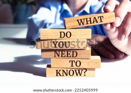 Close up on businessman holding a wooden block with "What Do You Need to Know?" message Royalty-Free Stock Photo #2252405999