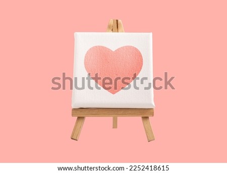 Heart picture, painting on mini canvas on wood easel on pink background. High quality photo