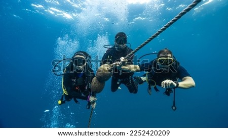 three professional diver checking his dive computer to as Royalty-Free Stock Photo #2252420209