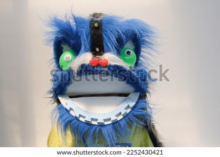 close up image of boy wears a blue lion dance head costume