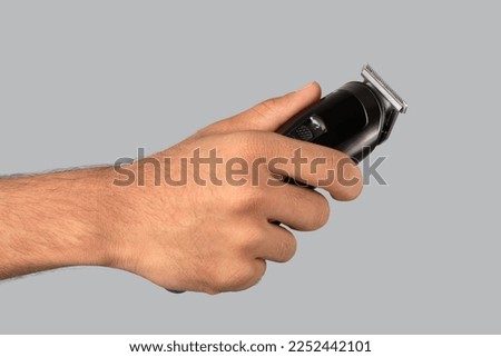 Man's hand holds a hair clipper	
