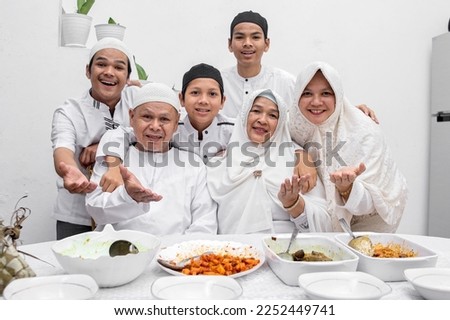 Smiling and happy muslim family showing delicious Eid food dishes with various food at dining room Royalty-Free Stock Photo #2252449741