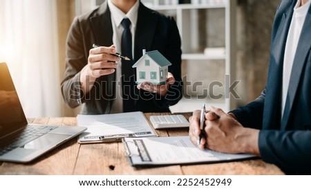 Real estate broker agent presenting and consult to customer to decision making sign insurance form agreement, home model, concerning mortgage loan offer 
