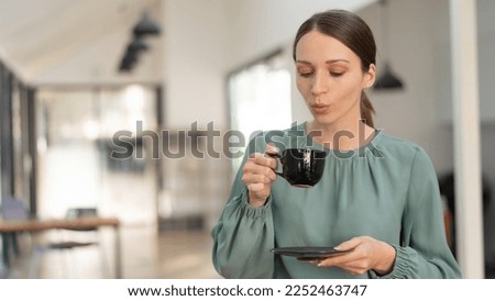 Smiling businesswoman leaning against whiteboard and drinking coffee