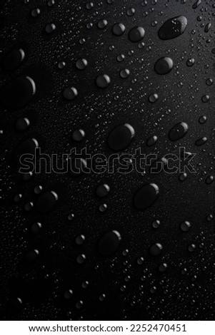 Water. Water drops on a black textured surface. Macro. Vertical image.