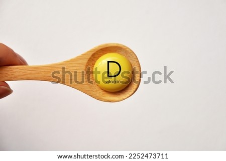 A tablet with the inscription Vitamin D on a spoon Royalty-Free Stock Photo #2252473711