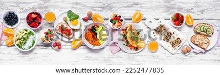 Healthy breakfast food table scene. Top down view over a white wood banner background. Omelette, nutritious bowl, toasts, granola bars, smoothie bowl, yogurts and fruits. Royalty-Free Stock Photo #2252477835