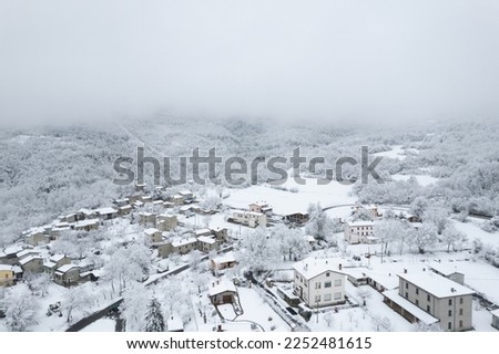 Aerial shot of winter landscape near italian apennines town covered in snow in a little town called Castelletto, Verncasca Italy