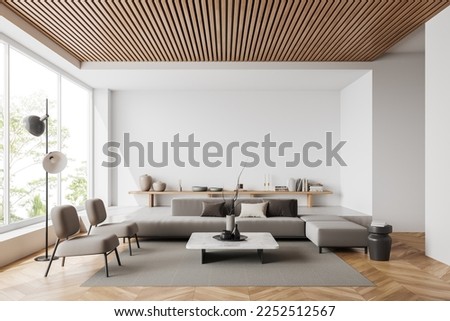 White living room interior with sofa and armchair, shelf with art decoration, carpet on hardwood floor. Panoramic window on tropics. Mockup copy space wall. 3D rendering Royalty-Free Stock Photo #2252512567