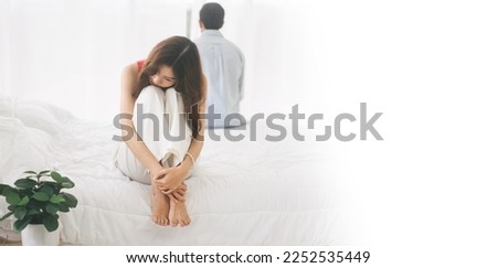 Married couple tired in problem of relationship to divorce concept. Woman hugged her knees sad and stress sitting on the bed. Banner size background with white space.