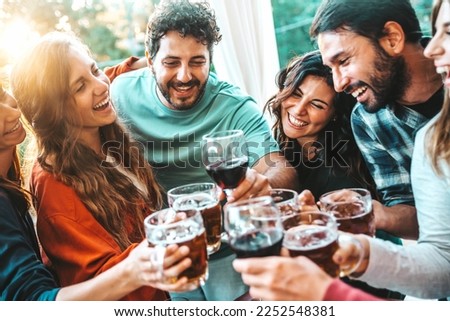 Happy group of friends cheering wine and beer glasses at cocktail bar restaurant - Trendy life style concept with guys and girls toasting drinks at summertime rooftop party - Youth culture concept