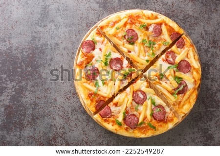 Tasty Americana Pizza with french fries, wurstel, cheese, tomato sauce and herbs close-up on a wooden board on the table. Horizontal top view from above
 Royalty-Free Stock Photo #2252549287