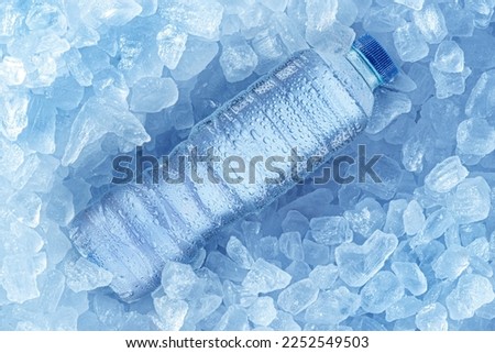 Cold bottle of water over ice cubes. Food and drink background. Royalty-Free Stock Photo #2252549503