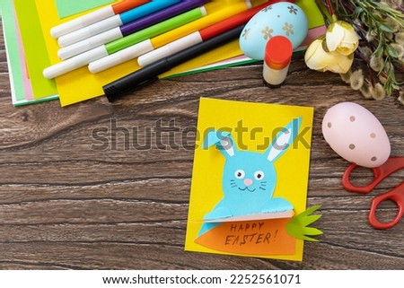 Easter congratulation card with Easter bunny on a wooden table. Copy space. Handmade. Project of children's creativity, handicrafts, crafts for kids.