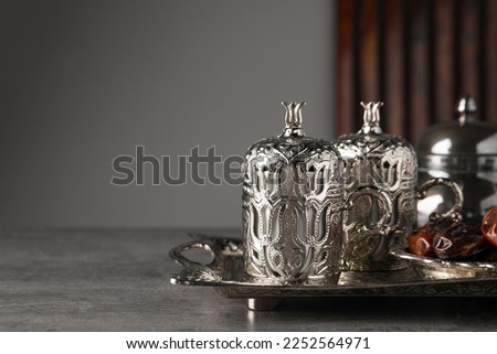 Tea and date fruits served in vintage tea set on grey textured table, space for text