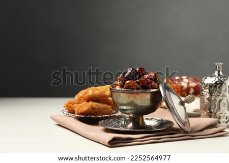 Tea, date fruits, Turkish delight and baklava dessert served in vintage tea set on white wooden table, space for text