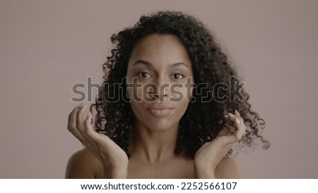 CU Portrait of attractive African-American female doing her skincare routine. Studio shot, soft lighting. No make up, clean skin