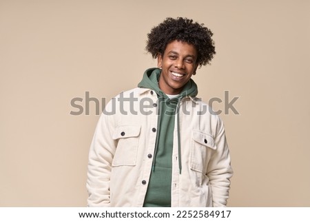 Happy young African American gen z guy isolated on beige background. Smiling hipster ethnic teen student, cool curly ethnic generation z teenager fashion model standing looking at camera, portrait.