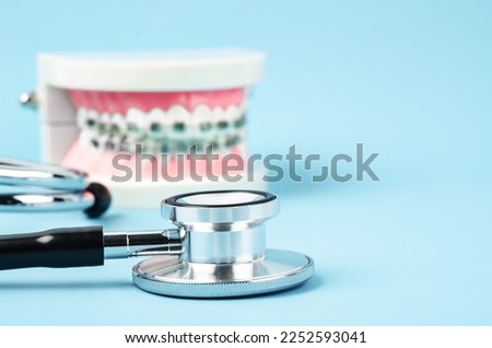 Medicine equipment stethoscope and metal wire dental braces on model teeth on blue background. Health dental care concept.