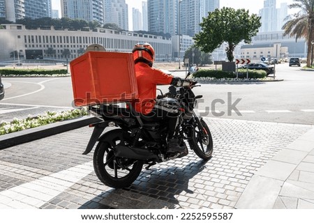 A food delivery courier is driving an order to a customer's home on a moped. takeaway food during quarantine. transport delivery of parcels at home. motorcycle rider with big backpack Royalty-Free Stock Photo #2252595587