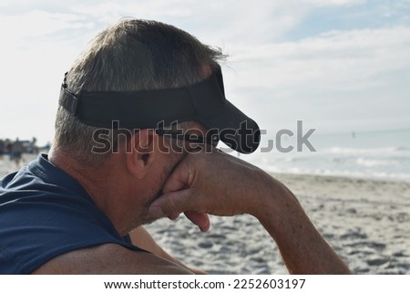 Pensive Caucasian man with sun visor looking at ocean