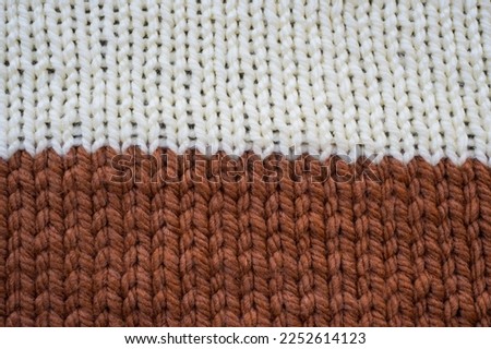Hand knitted plaid. Geometric seamless knitted pattern. The texture is knitted. Knitting. White and brown knitted background
