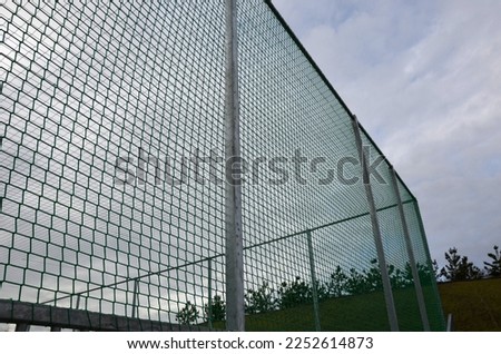  multifunctional outdoor playground for ball games at school. green artificial turf from a plastic carpet with lines. basketball hoops and soccer goals. around the grabbing high net and guardrails  Royalty-Free Stock Photo #2252614873