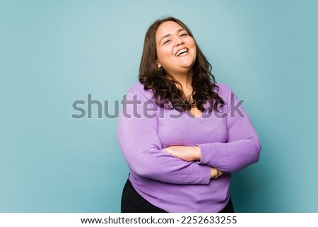 Attractive obese hispanic woman looking excited while laughing and having fun  Royalty-Free Stock Photo #2252633255