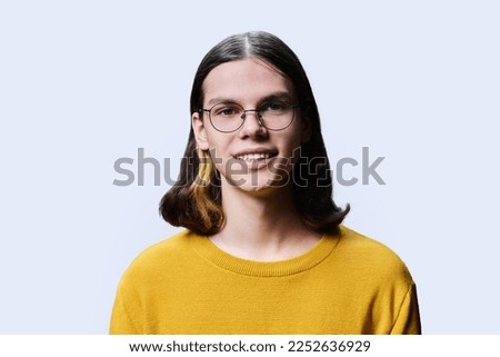 Headshot portrait of smiling teenage guy on light studio background