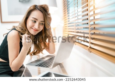 happy cute woman video fisting laptop in living room. pretty woman relaxing smiling cheer up internet people using laptop monitor. cheerful gorgeous woman make fisting cheer online person on screen.