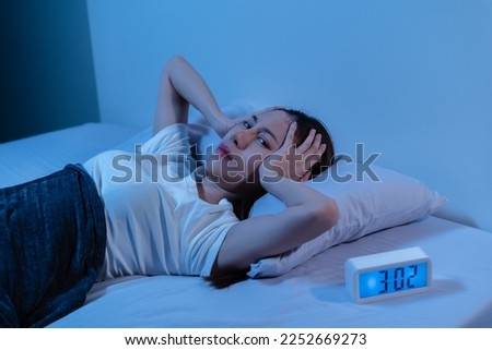 Annoyed, Stressed, asian young beautiful, pretty woman, girl suffering from insomnia, awake in bed at night, covering ears with hand because of disturbed loud noise, unable sleep. Restless people. Royalty-Free Stock Photo #2252669273