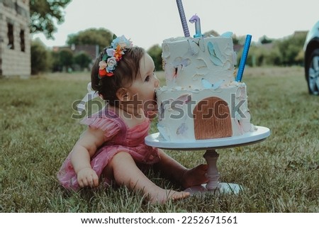 Baby girl first birthday cake smash outdoors. Little baby girl eating birthday cake during cake smash party.