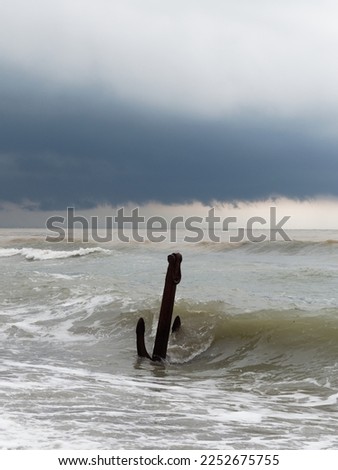 Anchor in a sea waves with storm clouds in the background