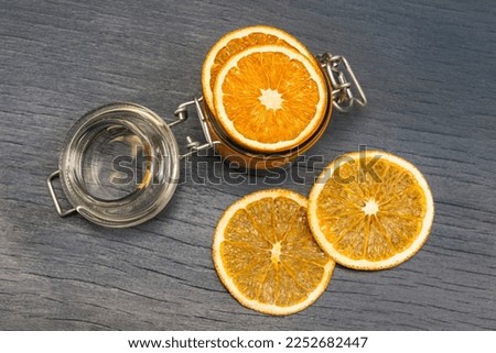 Orange slices in a glass jar and on the table. Flat lay. Grey background.