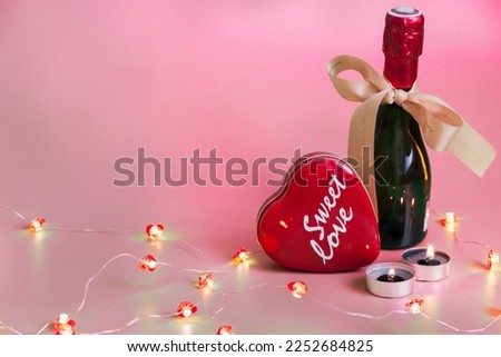 Sweet Love heart shaped red box, candles, champagne bottle with the ribbon, heart-shaped light bulbs chain on a isolated soft red background - valentine's day idea design decoration with copy space 