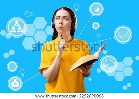 Portrait of thoughtful caucasian young woman wearing headphones holding book and pen at blue background with digital service. Concept of online education and business.