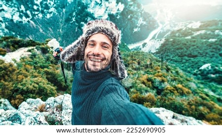 Happy male traveler taking selfie picture on top of the mountain - Travel blogger smiling at camera - Handsome young man taking self portrait with smart mobile phone device - Travel and technology 