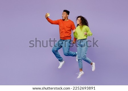 Full body fun young couple two friends family man woman of African American ethnicity wear casual clothes together do selfie shot on mobile cell phone isolated on pastel plain light purple background