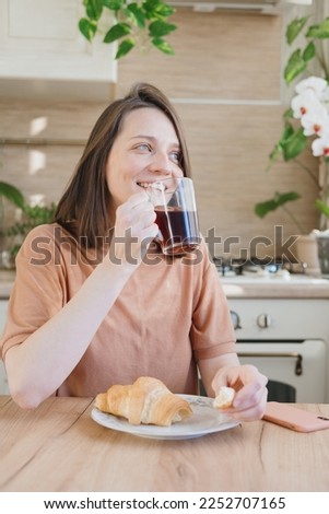 woman cooks drinks and eats croissant in morning for breakfast, brew a drip or purover. americano cappuccino. food and drink for lunch, happy woman eats and enjoys. lifestyle, concept of free life