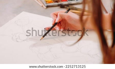 Sketching hobby. Painting art. Creative process. Closeup of female artist hand drawing lines with pencil on white canvas at workplace with free space.