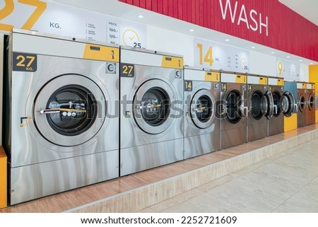 A row of qualified coin-operated washing machines in a public store. Concept of a self service commercial laundry and drying machine in a public room. Royalty-Free Stock Photo #2252721609
