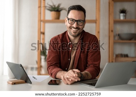 Happy smiling bearded businessman with glasses small business owner, company leader or sales manager, male CEO executive, successful entrepreneur looking at camera sitting in home office.  Royalty-Free Stock Photo #2252725759