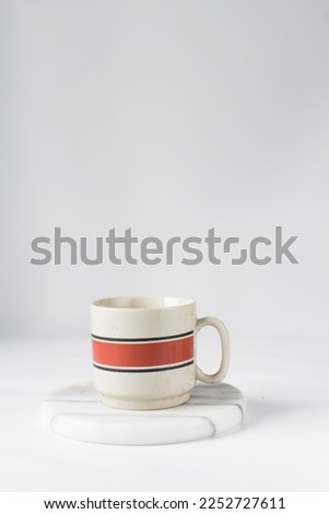 Cream and red ceramic cup on a white marble saucer, Cream and red teacup