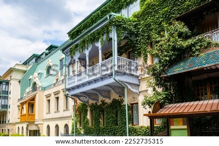 Carved wooden balcony and colorful buildings in historical Tbilisi, Georgia. Traditional decoration of Georgian house in Tiflis old town. Ivy on wall. Royalty-Free Stock Photo #2252735315
