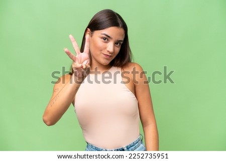 Young caucasian woman isolated on green chroma background happy and counting three with fingers Royalty-Free Stock Photo #2252735951