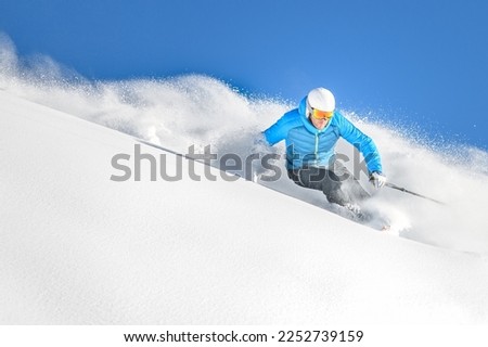 A skier on a carving turn in deep powder off-piste while free-riding Royalty-Free Stock Photo #2252739159