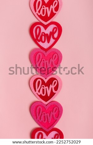 Vertical card with pink and red colored love hearts from above on light pink background. Romantic picture for Valentine's Day.