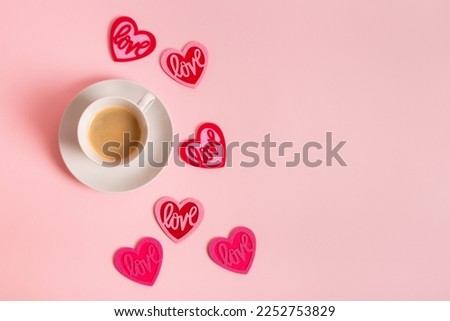 Morning coffee on Valentine's Day. A cup of americano coffee and set of red and pink hearts from above on pink background. Romantic lovely picture.