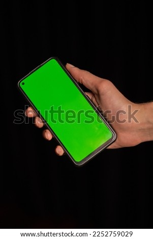 Smartphone in hand with green background.